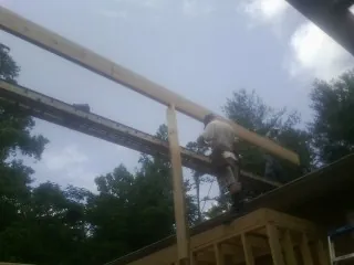 Carpenter setting a ridge beam over a new addition frame — Ice Dam Removal by Roofing Brothers in Laneview