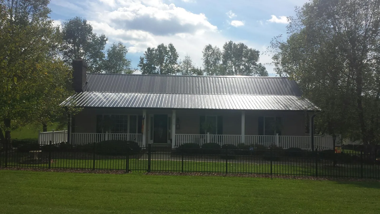 Gray metal roof on a brick ranch with a full width front porch — Gutter Guard Installation work by our crew in Laneview